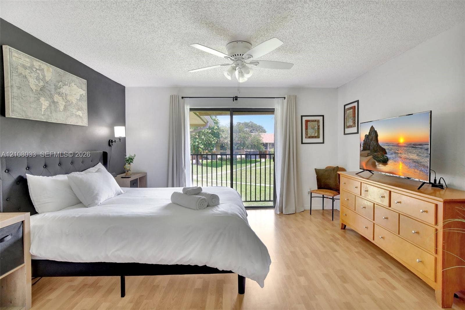 5821 Washington Street, #30, Hollywood, Hollywood, FL 33023 Wood-finish flooring, accent wall, ceiling fan with integrated lighting, and glass sliding door featuring a metal railing