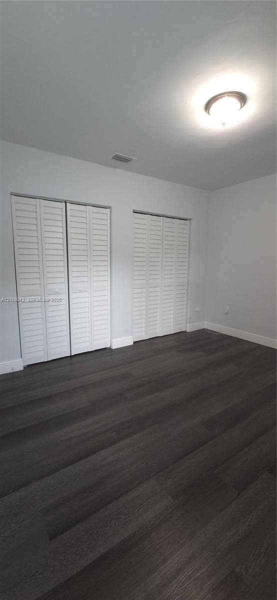 7176 SW 12th Street, #7176, Miami, Miami, FL 33144 Room featuring wood-finish flooring, two sets of white louvered-door closets, and a central flush-mount ceiling light fixture