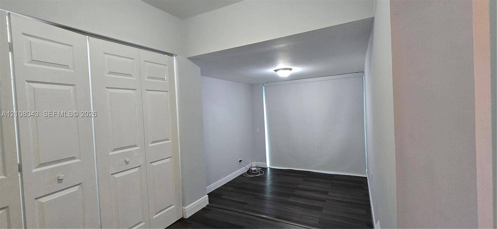 7176 SW 12th Street, #7176, Miami, Miami, FL 33144 Room interior featuring dark wood-finish flooring, white panel closet doors, neutral wall paint, and a flush-mount ceiling light fixture