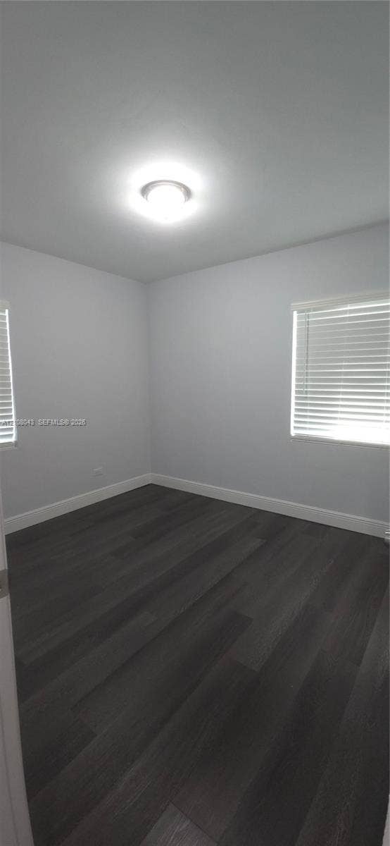 7176 SW 12th Street, #7176, Miami, Miami, FL 33144 Neutral-toned interior featuring wood-finish flooring, white walls, two windows with horizontal blinds, and a flush-mount ceiling light fixture