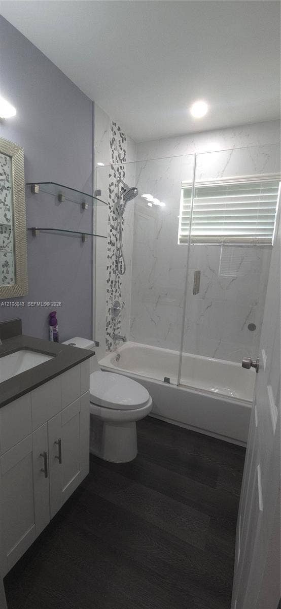 7176 SW 12th Street, #7176, Miami, Miami, FL 33144 Bathroom featuring a white shaker-style vanity with a dark solid-surface countertop, wood-finish flooring, a combination tub and shower with a glass panel enclosure, and tile wall accents