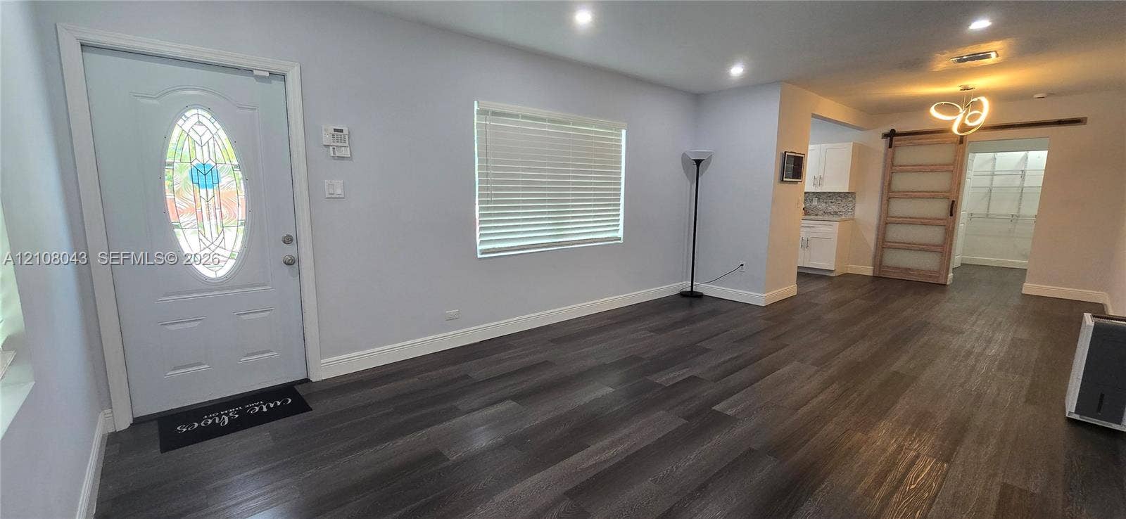 7176 SW 12th Street, #7176, Miami, Miami, FL 33144 Interior featuring wood-finish flooring, recessed lighting, an oval-glass paneled entry door, a sliding barn-style door, and built-in white cabinetry