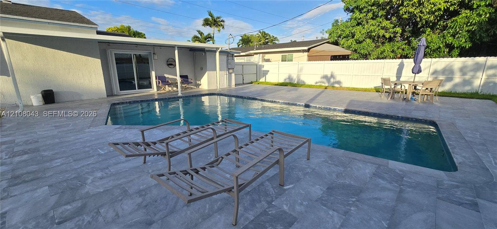 7176 SW 12th Street, #7176, Miami, Miami, FL 33144 Backyard featuring a paved stone patio, an in-ground swimming pool with tile trim, a covered exterior area, and a white vinyl perimeter fence