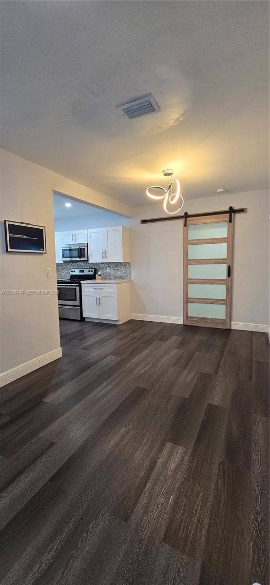 7176 SW 12th Street, #7176, Miami, Miami, FL 33144 Wood-finish flooring, sliding barn door with frosted glass panels, modern multi-ring chandelier, and white cabinetry
