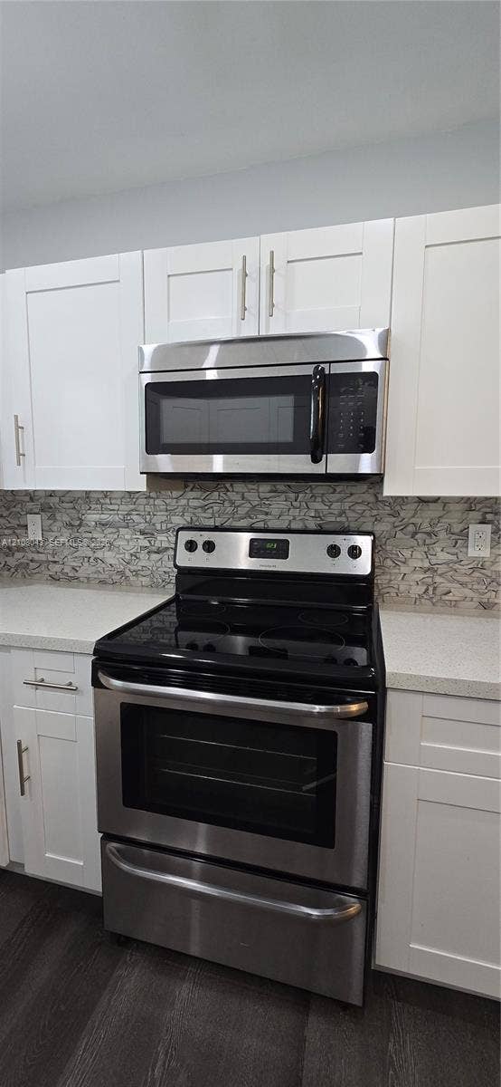 7176 SW 12th Street, #7176, Miami, Miami, FL 33144 Shaker-style white cabinetry, stainless steel microwave, stainless steel electric range, stone-mosaic backsplash, and solid-surface countertops