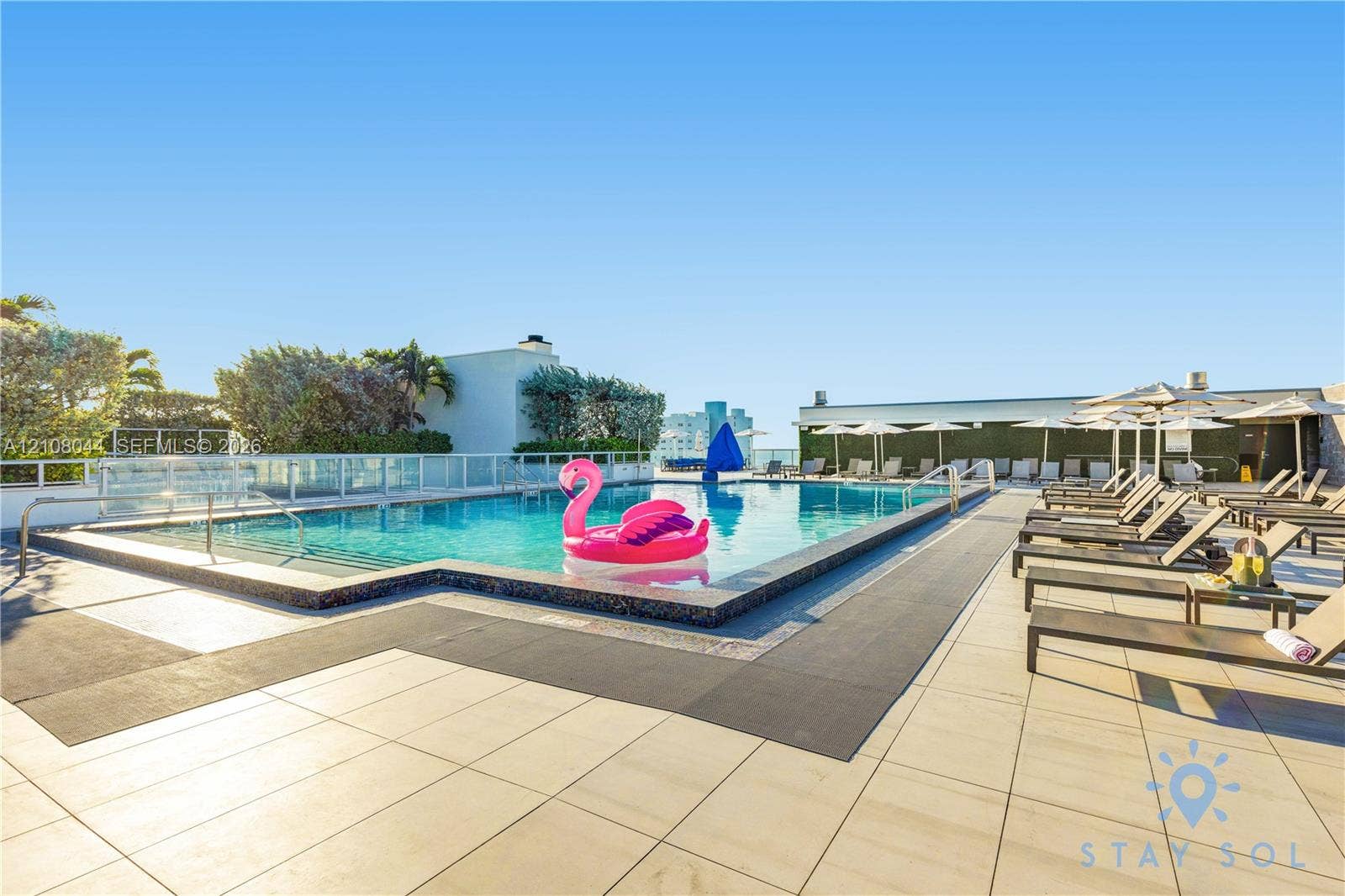 Rooftop swimming pool with tile surround, glass panel railing, and integrated metal handrails