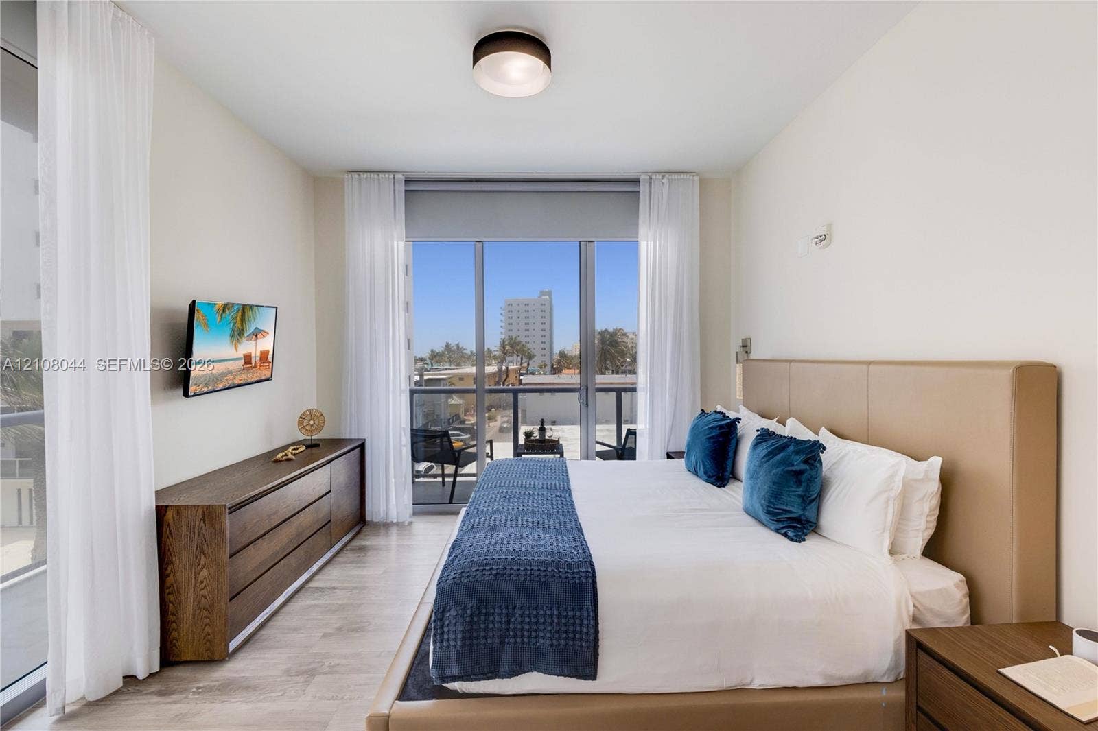 Wood-finish flooring, floor-to-ceiling sliding glass doors, private balcony, and flush-mount ceiling lighting
