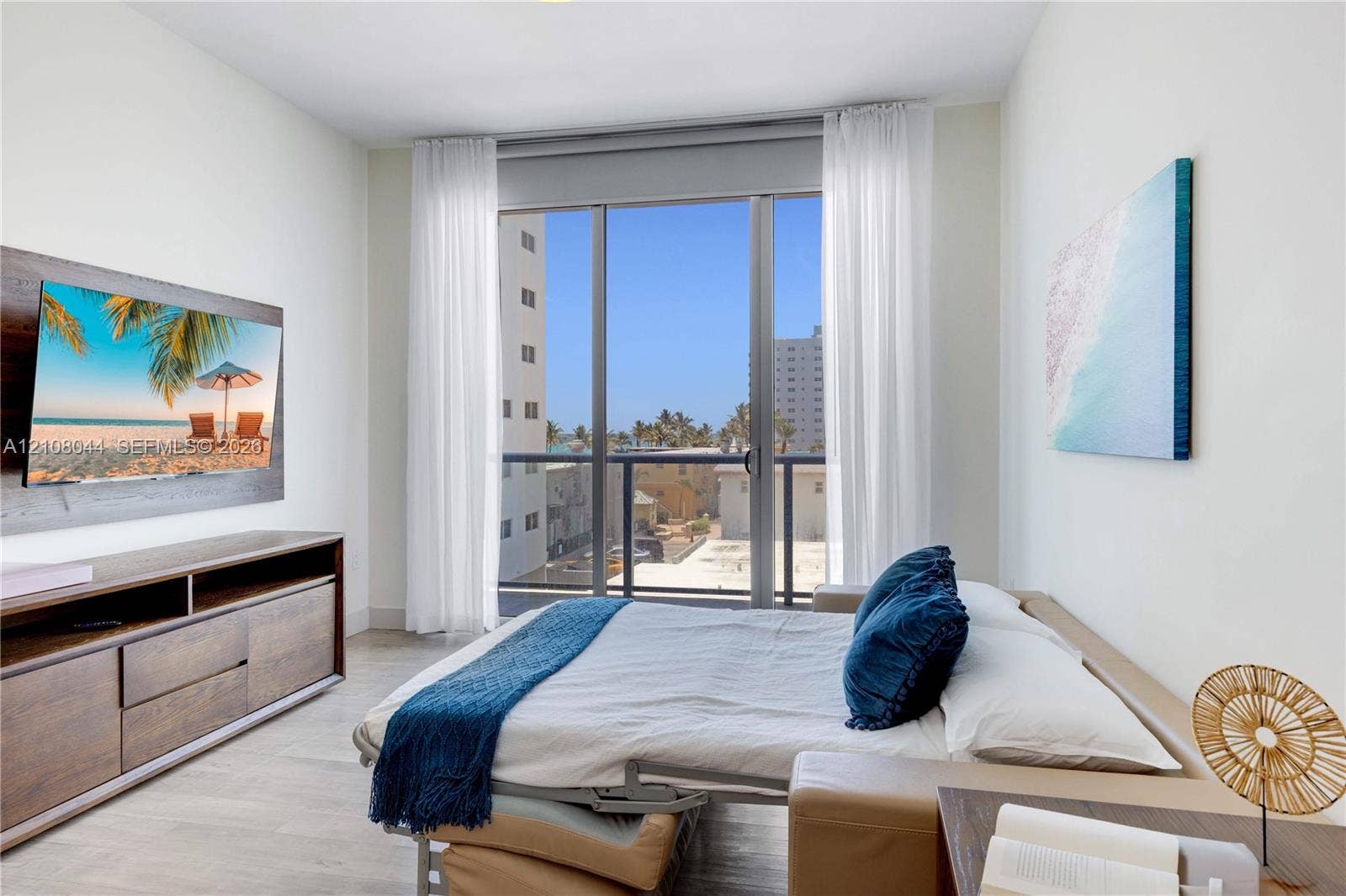 Floor-to-ceiling glass sliding doors opening to a balcony, light-toned wood-finish flooring, and crisp neutral wall finish