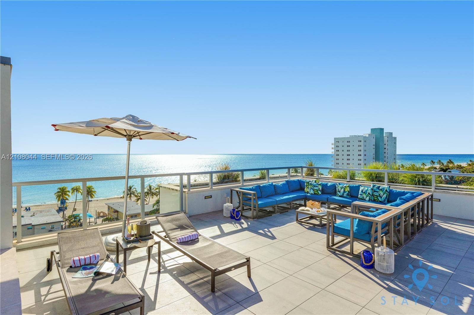 Expansive open-air rooftop terrace featuring large-format tile flooring and a perimeter glass-panel railing
