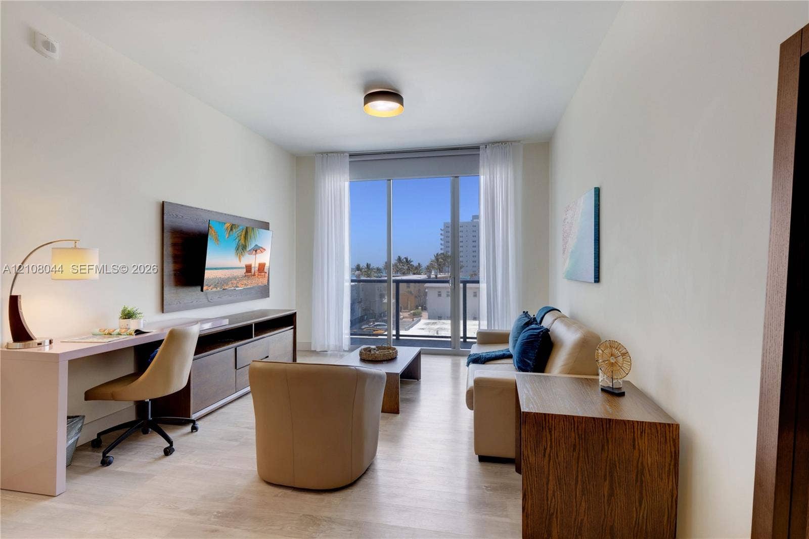 Living area featuring wood-finish flooring, floor-to-ceiling glass paneling, a private balcony, and a built-in dark wood-tone media console