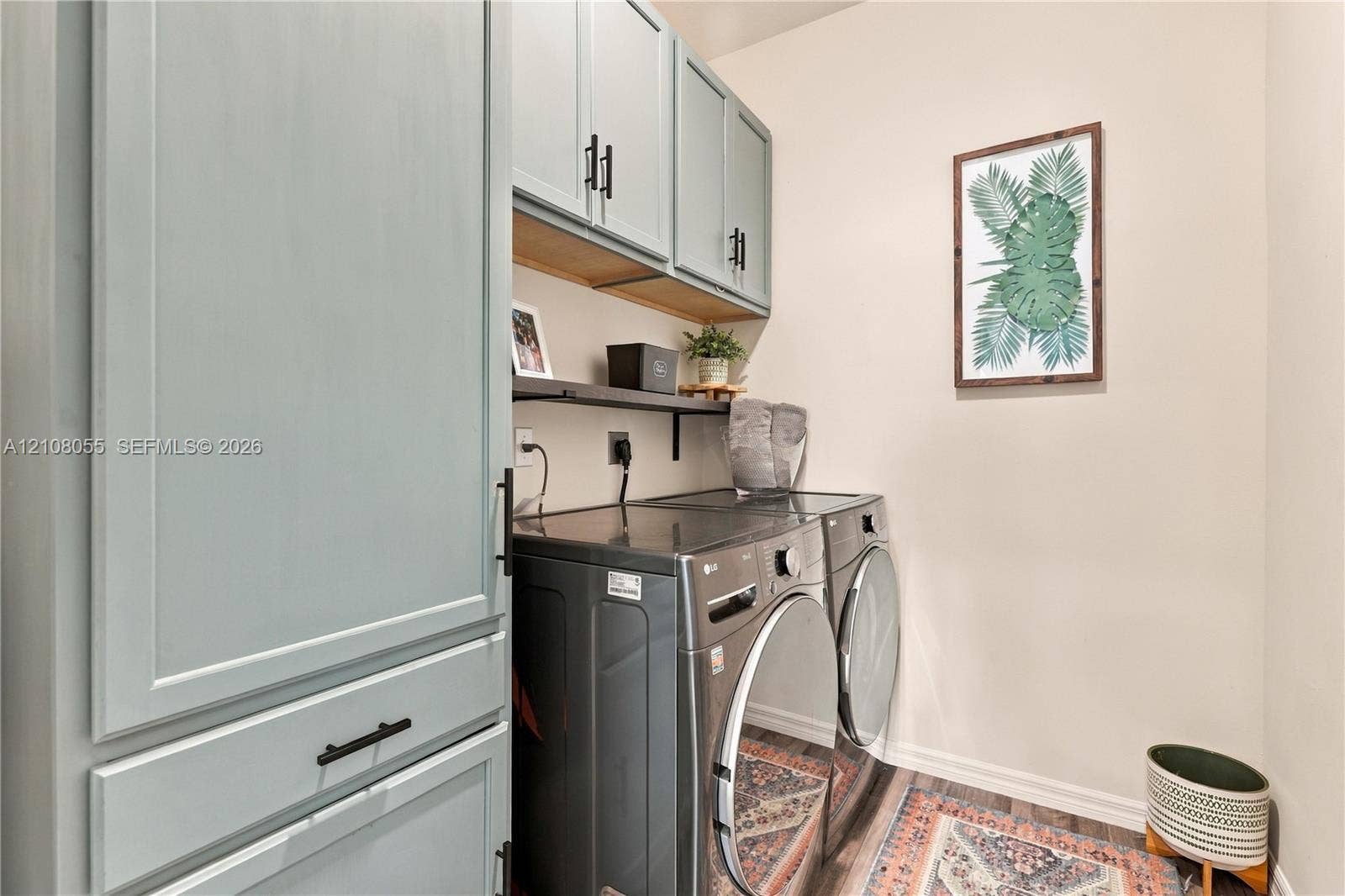 557 SW Lacroix Avenue, Port St Lucie, FL 34953 Utility area featuring custom-painted cabinetry with matte black hardware, integrated open shelving, and wood-finish flooring