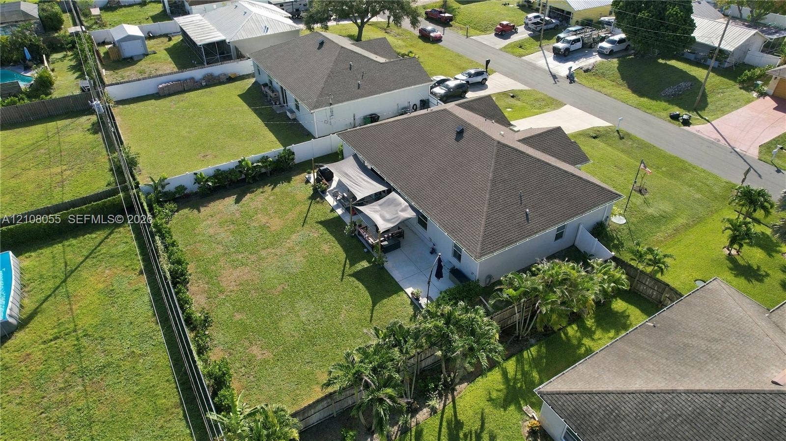 557 SW Lacroix Avenue, Port St Lucie, FL 34953 Aerial perspective of a property featuring a concrete patio, fenced backyard, and hipped roofline