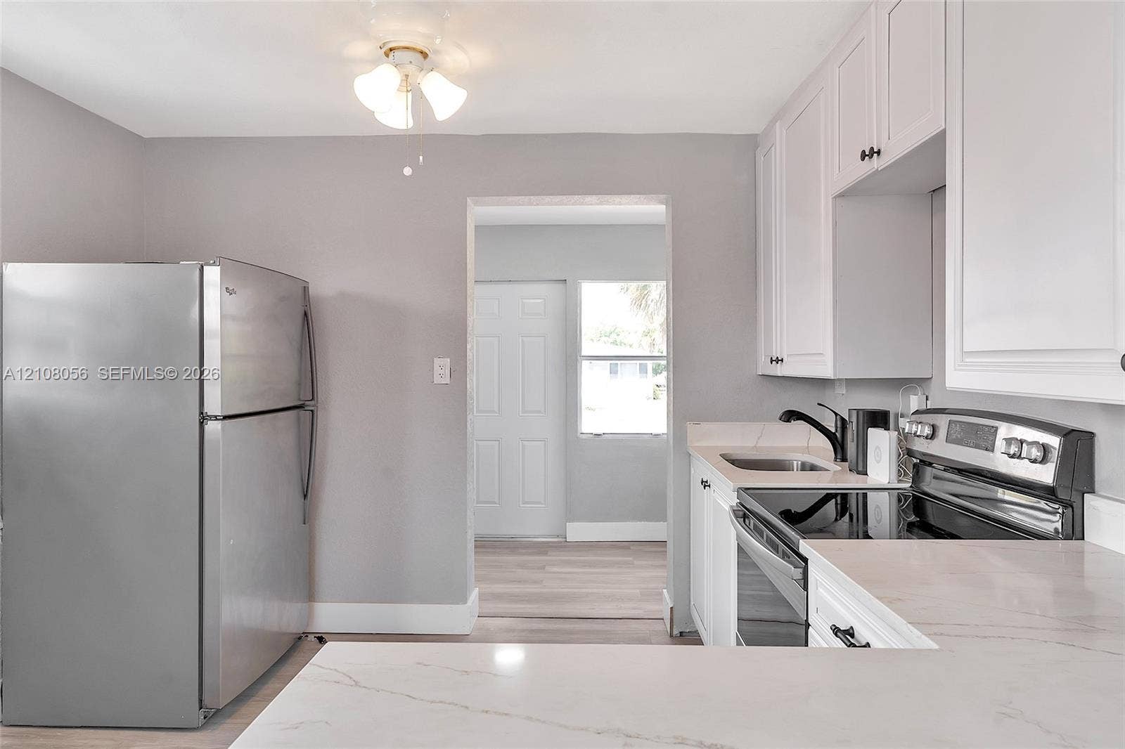 1444 W 28th Street, Riviera Beach, FL 33404 Kitchen featuring white shaker-style cabinetry, solid-surface countertops with grey veining, stainless steel refrigerator, stainless steel electric range, and matte black faucet