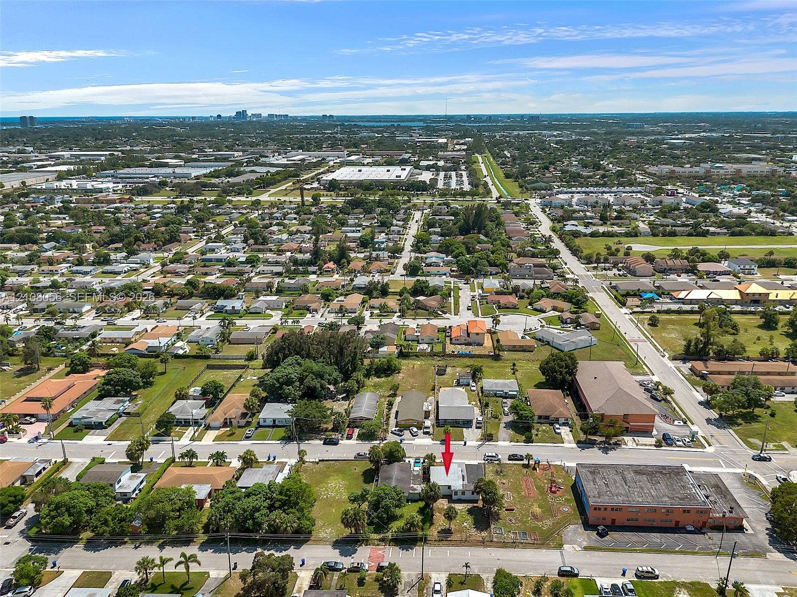 1444 W 28th Street, Riviera Beach, FL 33404 Aerial perspective of a corner lot property featuring a single-story structure, fenced perimeter, and established landscaping