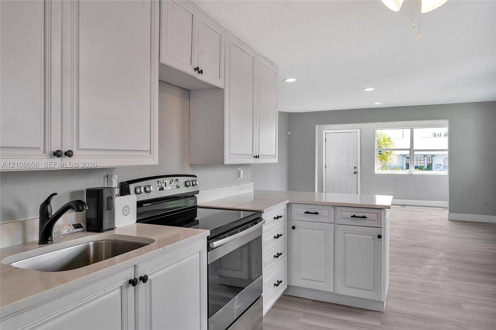 1444 W 28th Street, Riviera Beach, FL 33404 Kitchen featuring shaker-style cabinetry, solid surface countertops, stainless steel electric range, undermount sink with matte black faucet, and wood-finish flooring