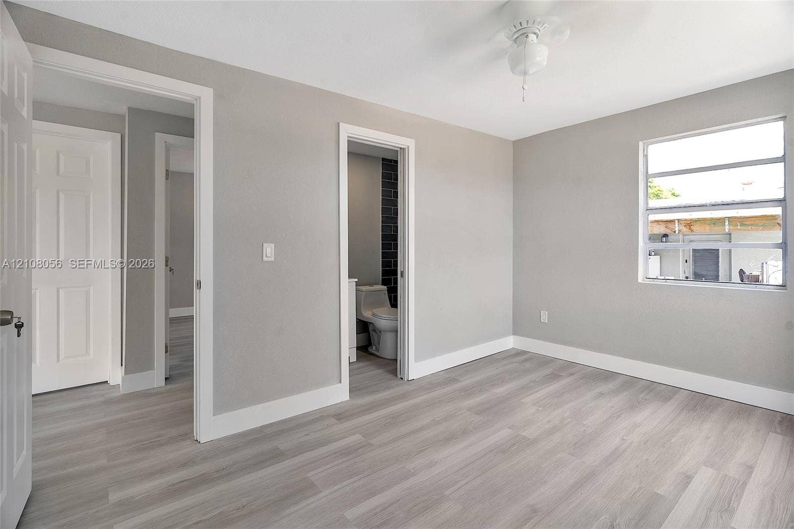 1444 W 28th Street, Riviera Beach, FL 33404 Neutral-toned interior room featuring wood-finish flooring, a ceiling fan, and white-paneled interior doors