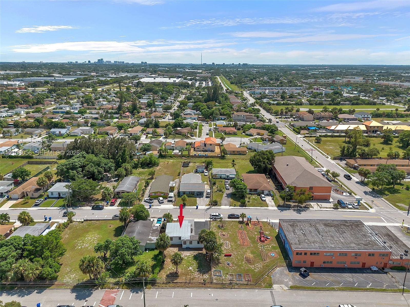 1444 W 28th Street, Riviera Beach, FL 33404 Aerial perspective featuring a single-story residence with a pitched roof, situated on a rectangular lot with mature palm trees
