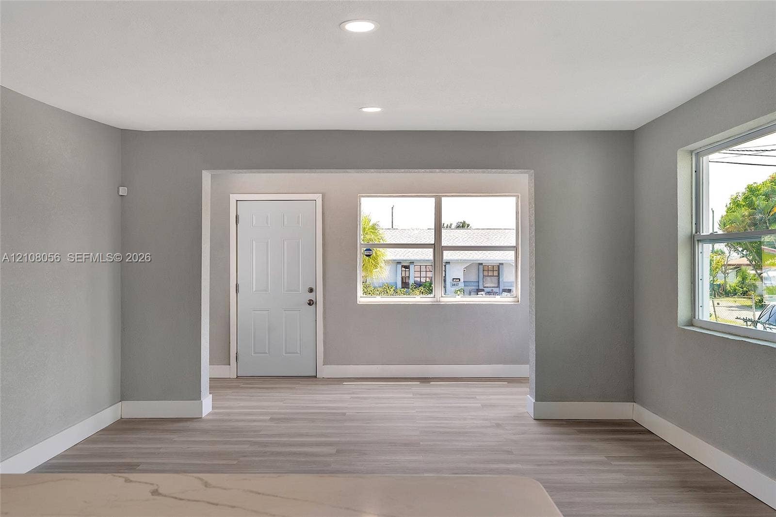 1444 W 28th Street, Riviera Beach, FL 33404 Interior space featuring wood-finish flooring, recessed lighting, neutral wall paint, white trim, and oversized windows