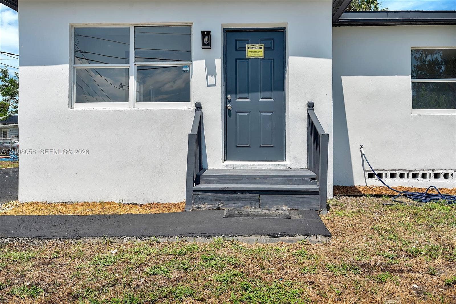1444 W 28th Street, Riviera Beach, FL 33404 Stucco exterior featuring dual-pane windows, a dark-toned solid front door, and a dedicated walkway with matching painted steps and railings