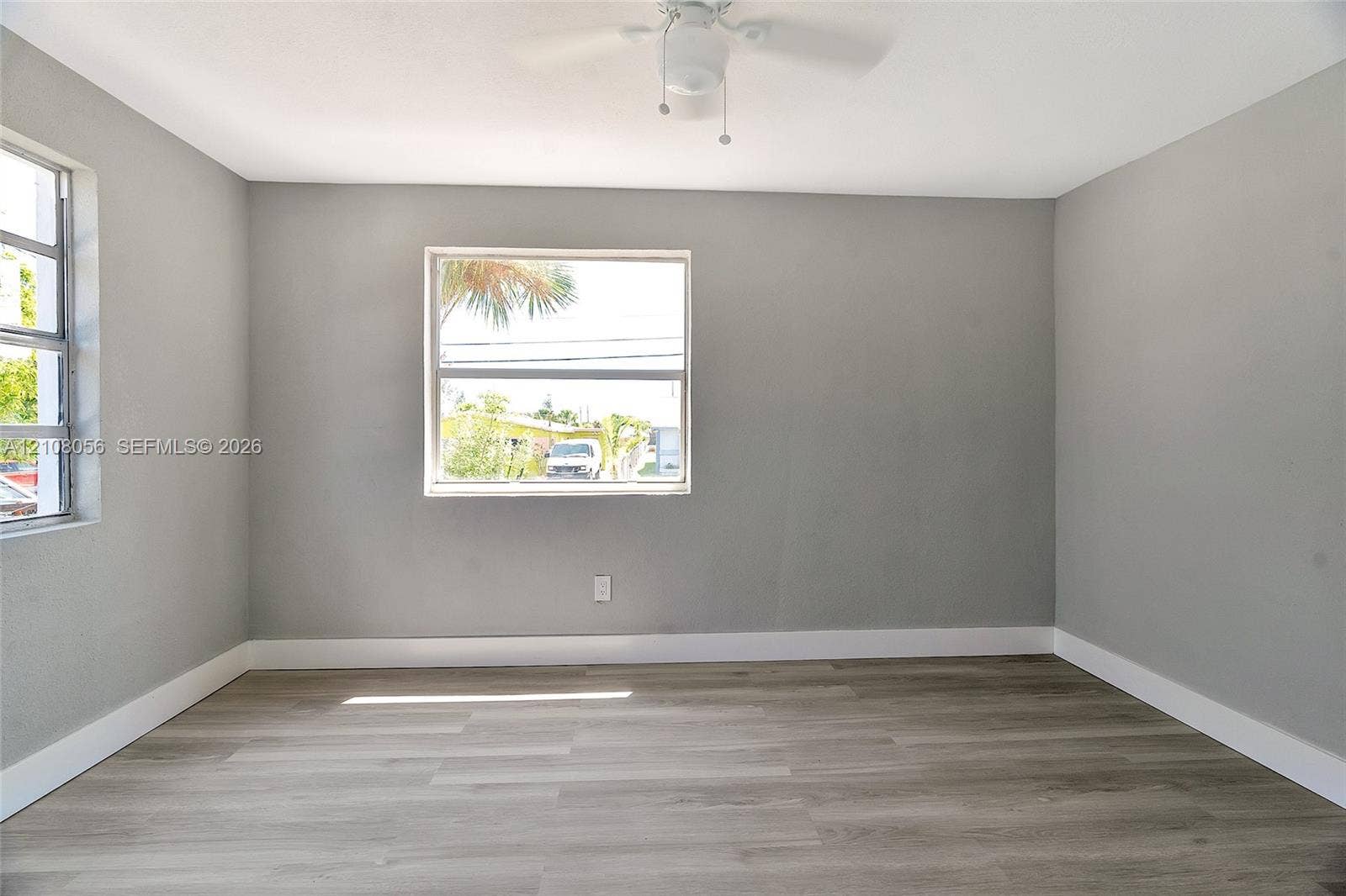 1444 W 28th Street, Riviera Beach, FL 33404 Room featuring neutral-toned walls, wood-finish flooring, and a ceiling-mounted fan with integrated lighting