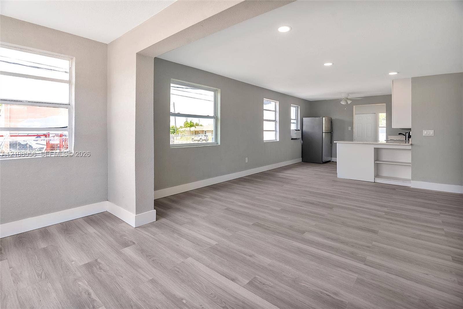 1444 W 28th Street, Riviera Beach, FL 33404 Open-concept interior featuring wood-finish flooring, recessed lighting, neutral wall tones, and a kitchen peninsula with built-in cabinetry