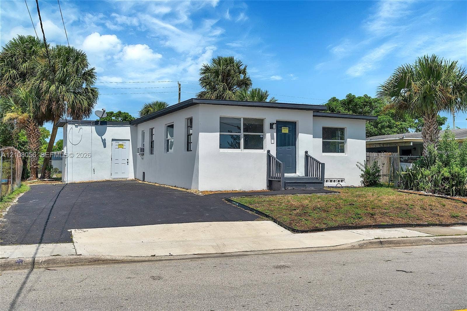 1444 W 28th Street, Riviera Beach, FL 33404 Stucco exterior featuring a flat roofline, asphalt driveway, and front entryway with dark-toned railings