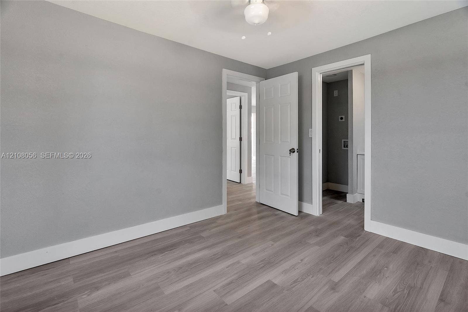 1444 W 28th Street, Riviera Beach, FL 33404 Interior space featuring wood-finish flooring, light gray walls, six-panel interior doors, and a ceiling-mounted light fixture