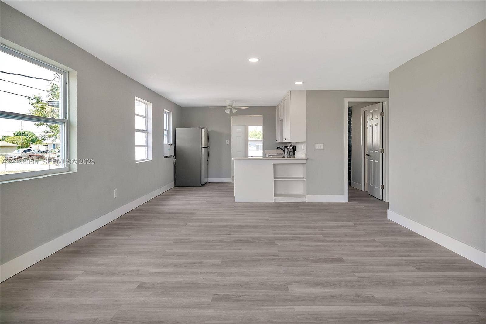 1444 W 28th Street, Riviera Beach, FL 33404 Open-concept interior featuring wood-finish flooring, recessed lighting, and white cabinetry with a built-in peninsula