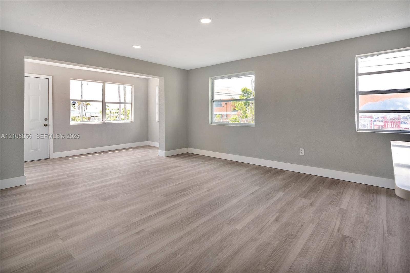 1444 W 28th Street, Riviera Beach, FL 33404 Open-concept interior space featuring light-tone wood-finish flooring, recessed lighting, and multiple horizontal sliding windows