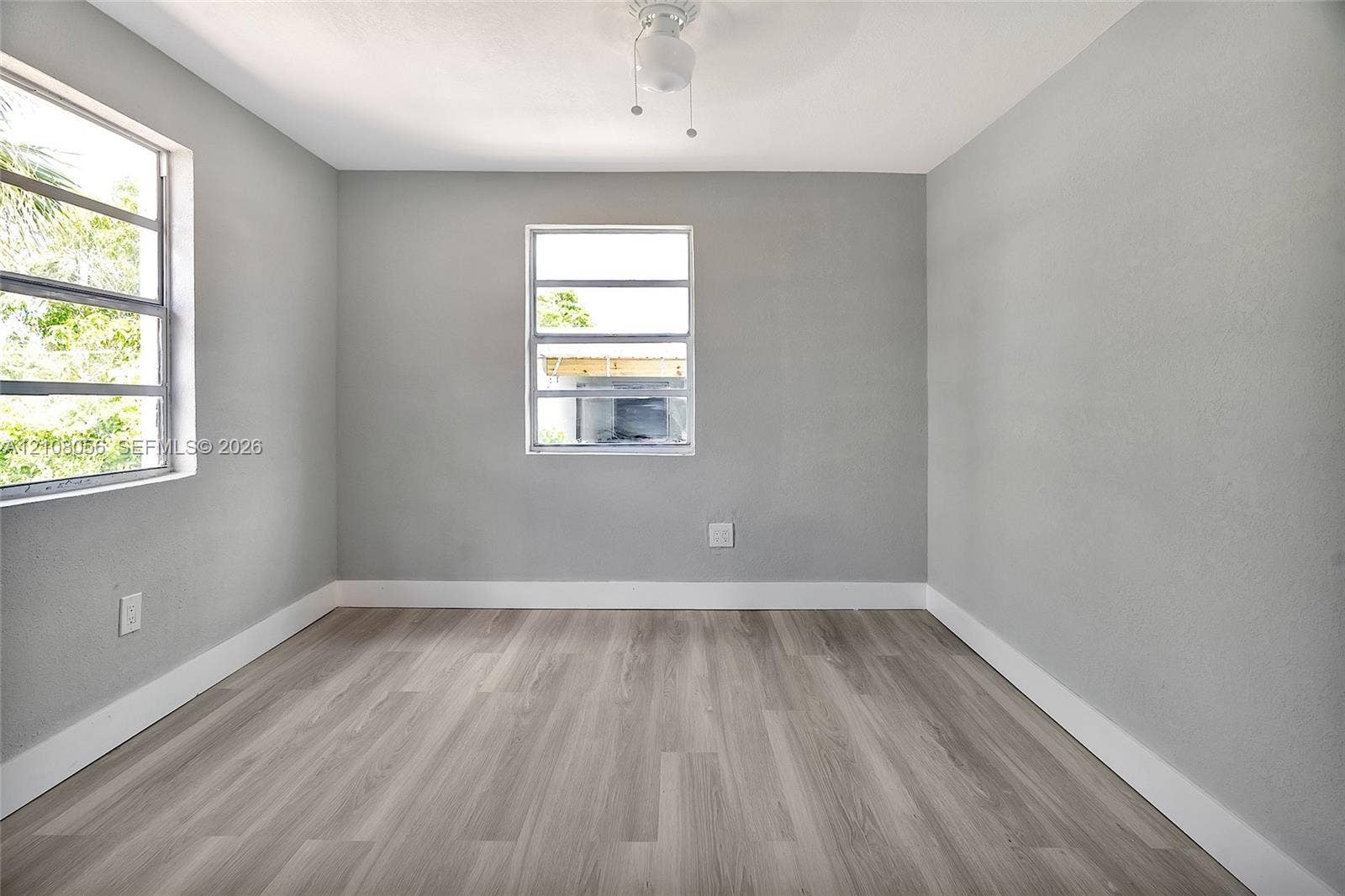 1444 W 28th Street, Riviera Beach, FL 33404 Room featuring wood-finish flooring, two horizontal-pane windows, and a central ceiling light fixture