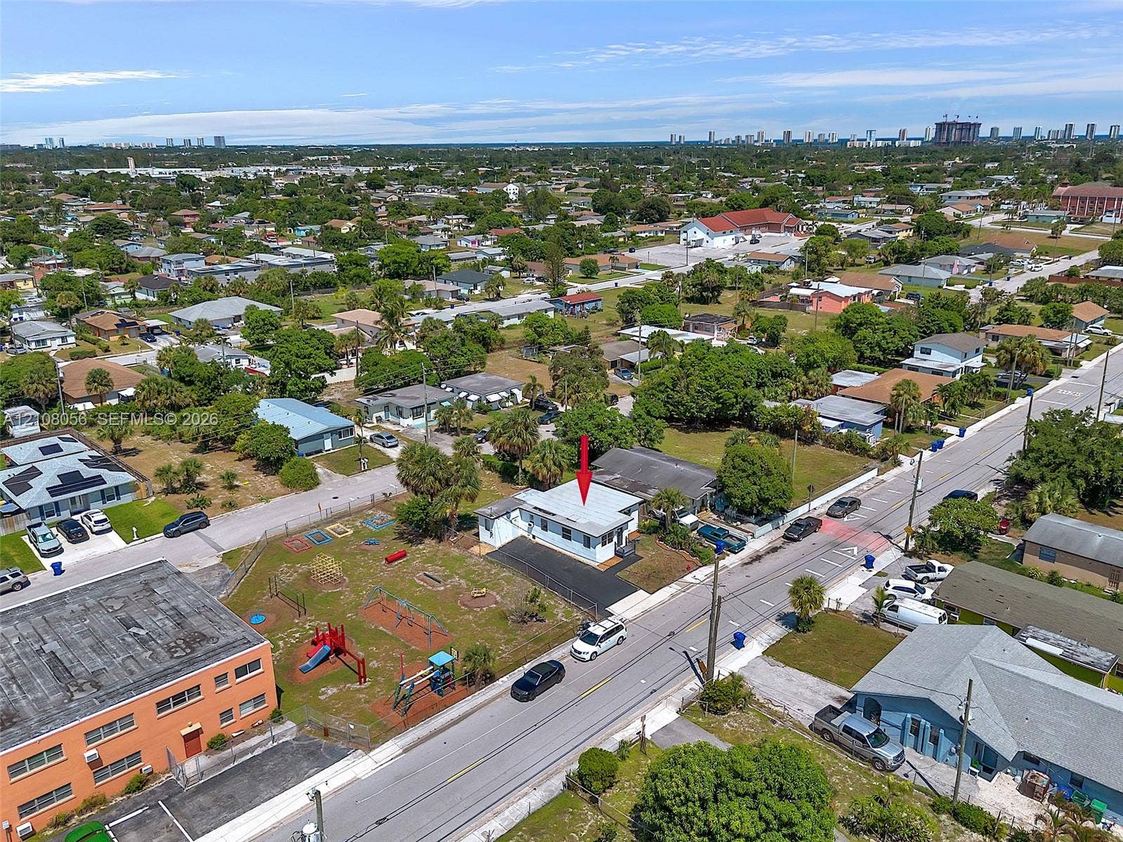 1444 W 28th Street, Riviera Beach, FL 33404 Single-story residence featuring a light-colored exterior finish, a metal roof, and an asphalt driveway