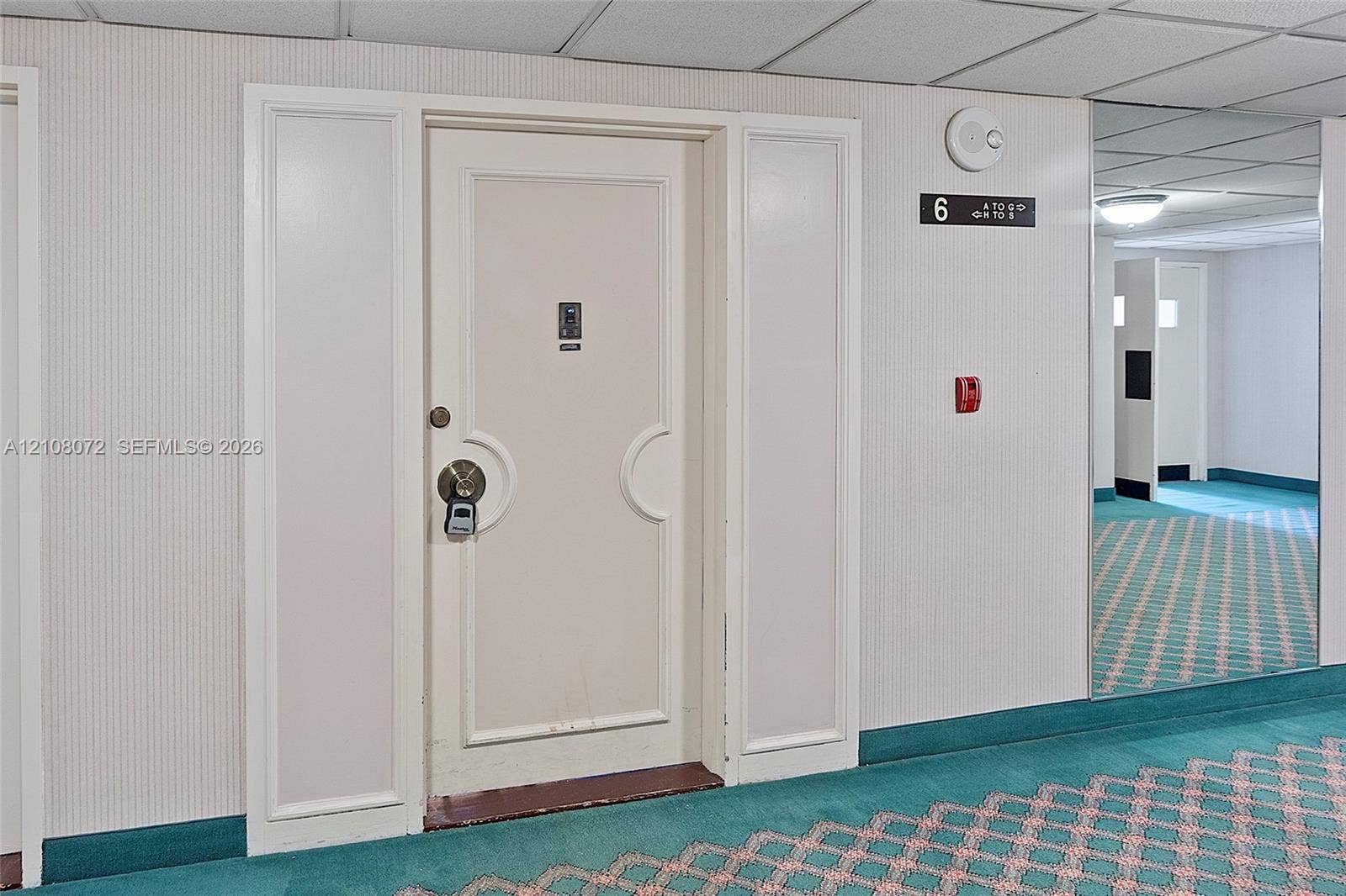 Entry door with dual sidelights, brushed metallic hardware, integrated security feature, and wall-mounted floor signage