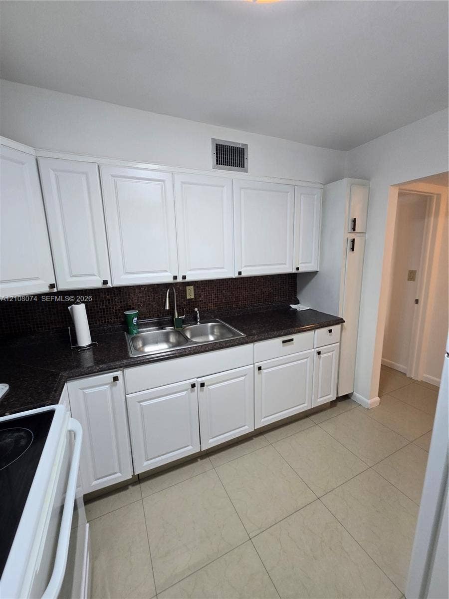 250 180th Drive, #202, Sunny Isles Beach, Sunny Isles Beach, FL 33160 Kitchen featuring white cabinetry, dark countertops, a double-basin stainless steel sink, and light-toned tile flooring