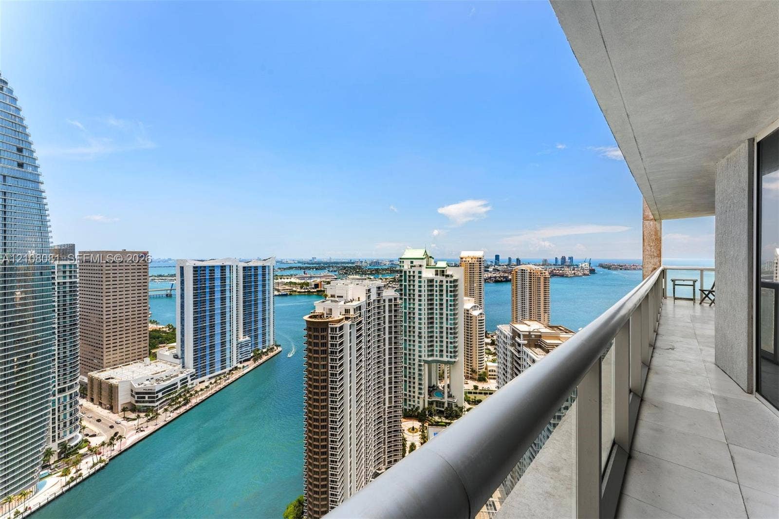 495 Brickell Avenue, #4502, Miami, FL 33131 Covered balcony featuring neutral tile flooring, glass and metal railings, and panoramic coastal and metropolitan skyline scenery
