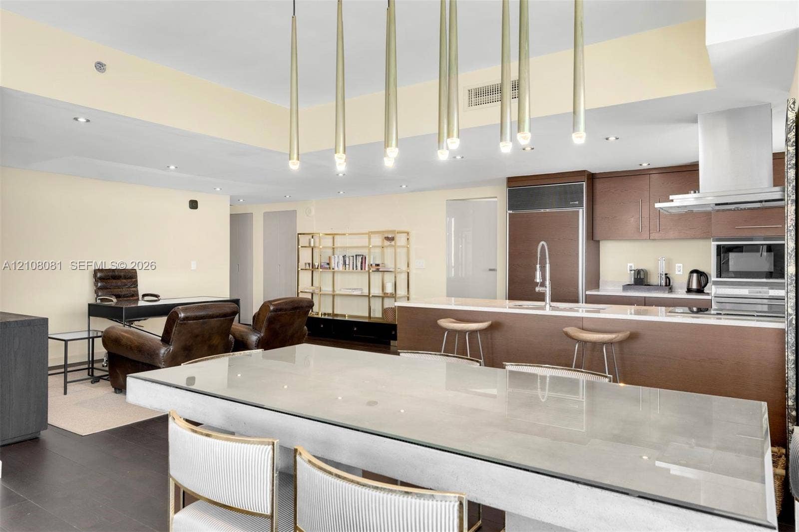 495 Brickell Avenue, #4502, Miami, FL 33131 Open concept kitchen featuring dark wood-finish cabinetry, built-in stainless steel appliances, a center island with a stone countertop, and custom multi-pendant lighting