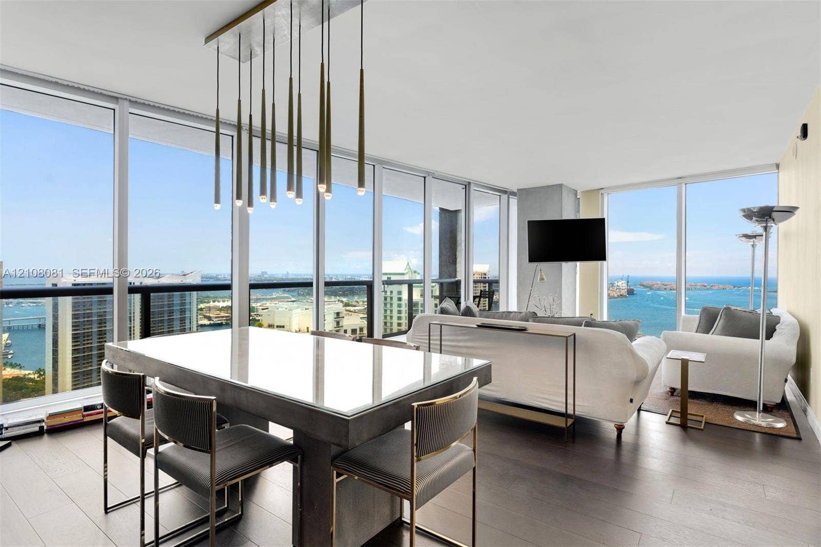 495 Brickell Avenue, #4502, Miami, FL 33131 Floor-to-ceiling windows, wood-finish flooring, and a linear pendant light fixture featuring multiple metallic cylindrical elements