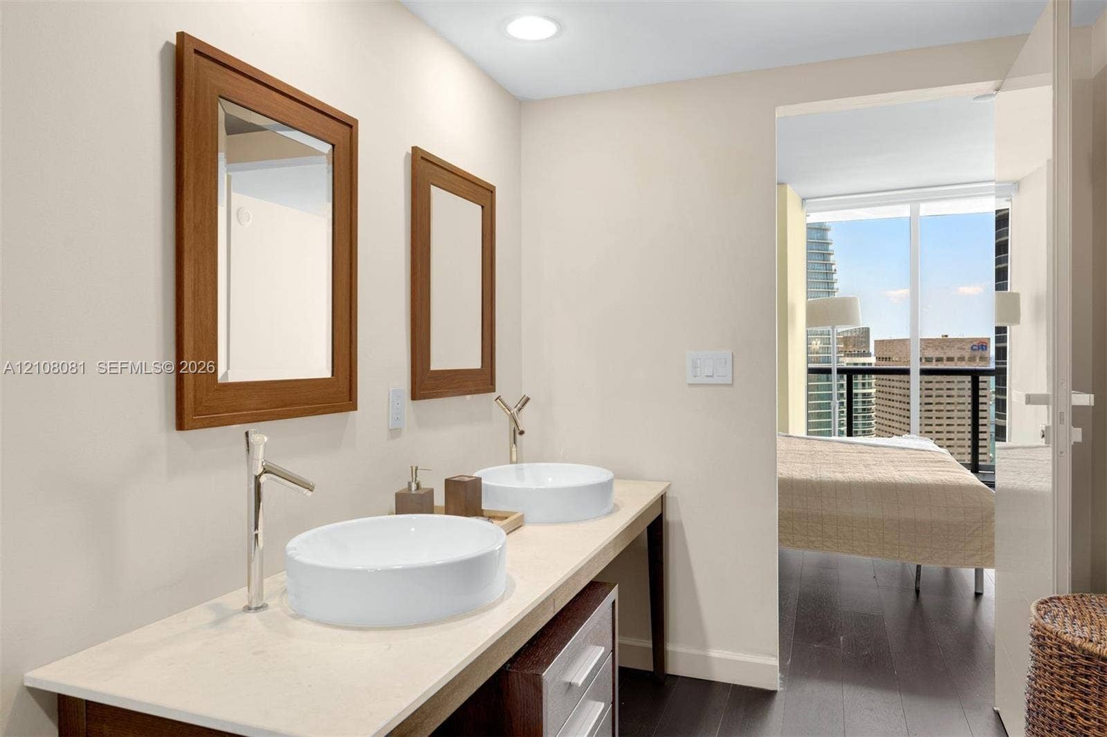 495 Brickell Avenue, #4502, Miami, FL 33131 Dual-basin vanity featuring white vessel sinks, quartz countertops, chrome high-arc faucets, and wood-framed mirrors
