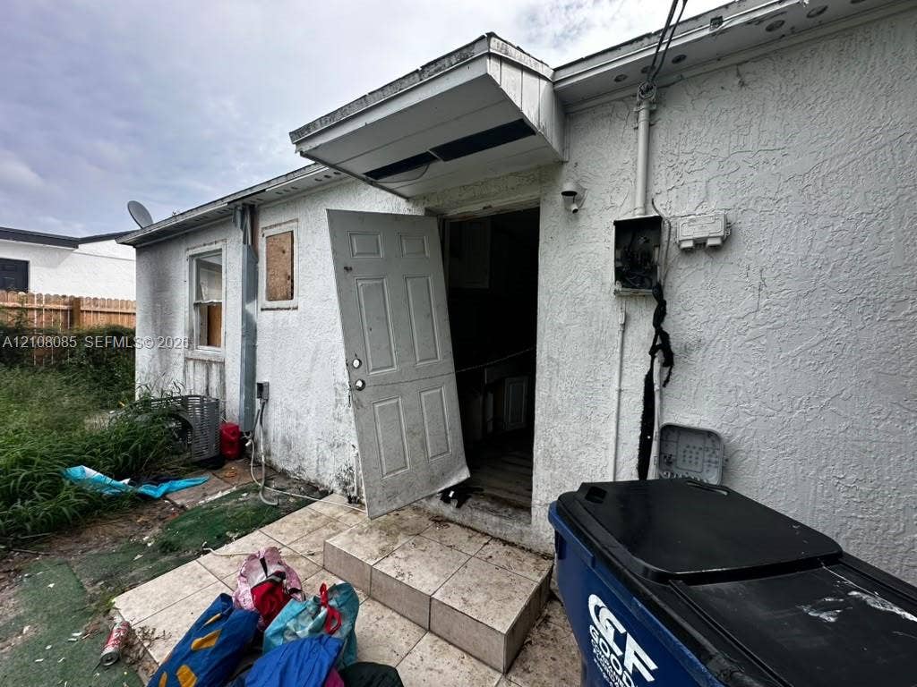 Stucco exterior featuring a paved entry platform and exterior lighting fixture