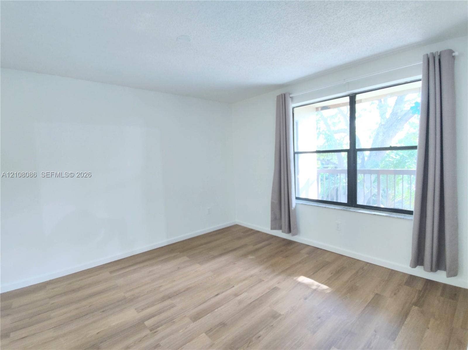 4401 W Mcnab Road, Pompano Beach, FL 33069 Room featuring wood-finish flooring, white walls, and a large window with a stone sill