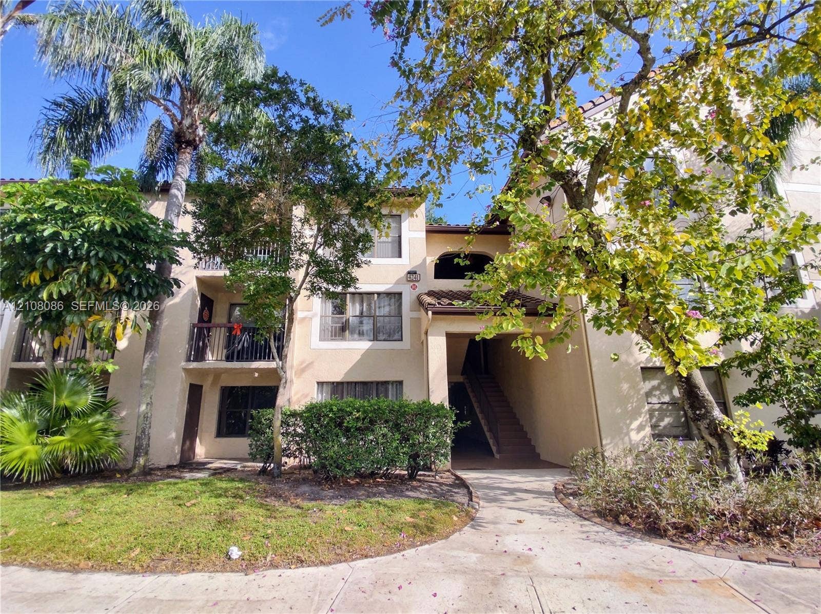 4401 W Mcnab Road, Pompano Beach, FL 33069 Multi-story exterior featuring a stucco facade, clay tile roof accents, private second-story balconies with iron railings, and concrete walkways