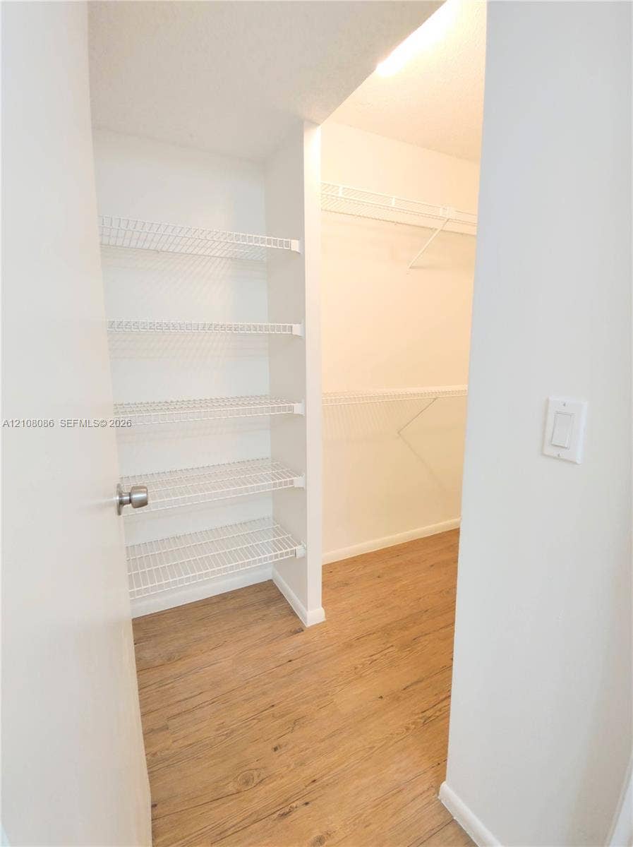 4401 W Mcnab Road, Pompano Beach, FL 33069 Walk-in closet featuring wood-finish flooring, white walls, and integrated wire shelving