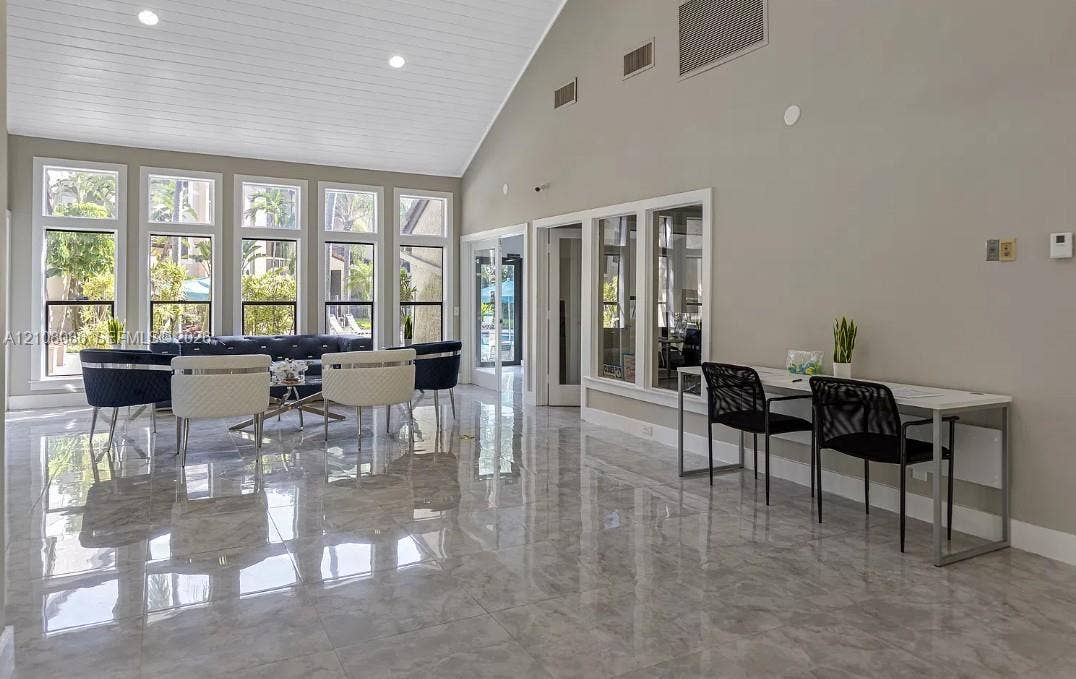 4401 W Mcnab Road, Pompano Beach, FL 33069 Vaulted ceiling with tongue-and-groove paneling, polished stone-finish tile flooring, and floor-to-ceiling windows