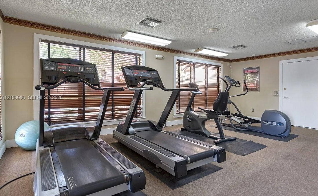 4401 W Mcnab Road, Pompano Beach, FL 33069 Fitness center featuring wall-to-wall carpeting, multiple windows with horizontal blinds, and overhead fluorescent lighting