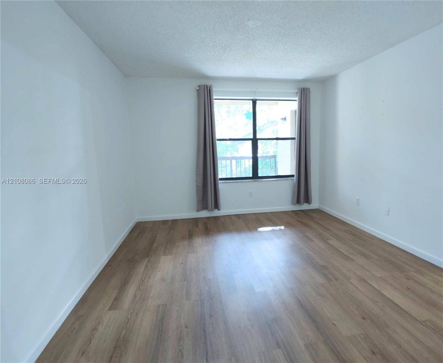 4401 W Mcnab Road, Pompano Beach, FL 33069 Neutral interior space featuring wood-finish flooring, white walls, and a window with black framing