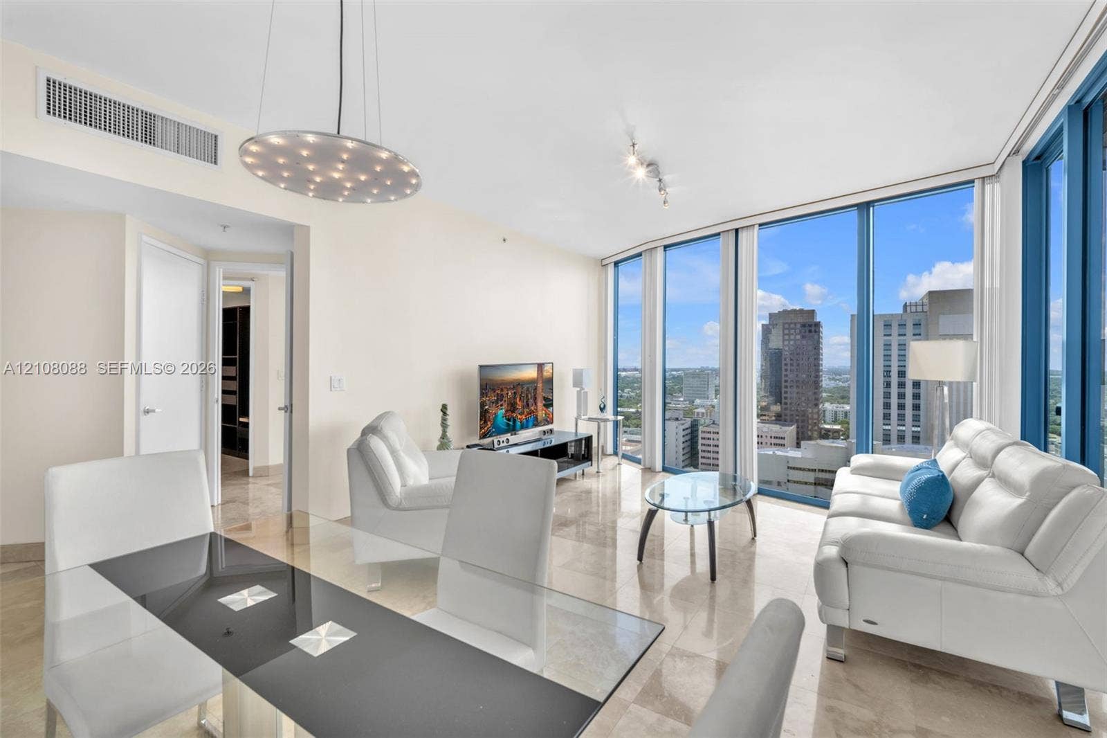 333 Las Olas Way, #2601, Fort Lauderdale, FL 33301 Open-concept interior featuring floor-to-ceiling windows, natural stone flooring, and a decorative disc-style pendant light