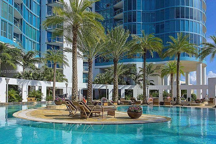 333 Las Olas Way, #2601, Fort Lauderdale, FL 33301 Outdoor swimming pool featuring a stone-tile deck, integrated landscaping with mature palm trees, and structural concrete columns