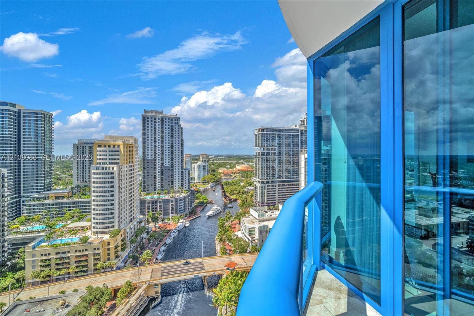 333 Las Olas Way, #2601, Fort Lauderdale, FL 33301 Private balcony with blue glass railing featuring floor-to-ceiling blue-tinted windows and stone-tiled flooring