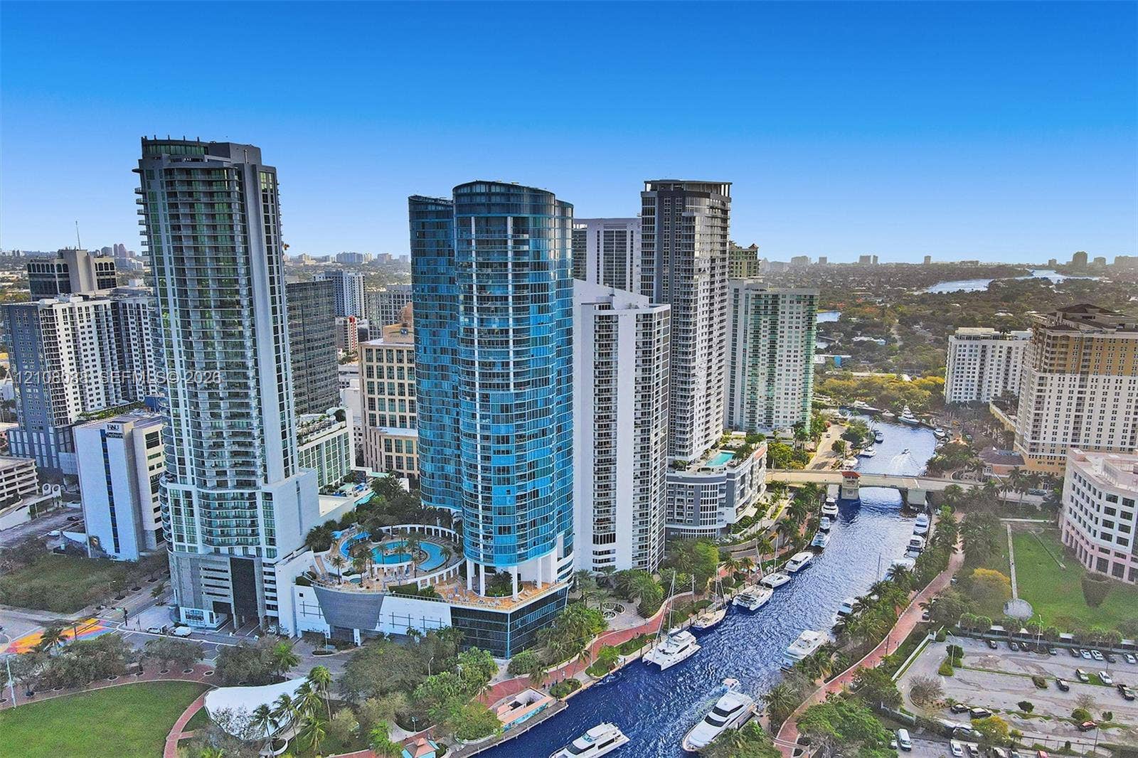 333 Las Olas Way, #2601, Fort Lauderdale, FL 33301 Aerial perspective of high-rise urban towers featuring glass-facade architecture, a multi-level swimming pool terrace, and water-front placement along a canal