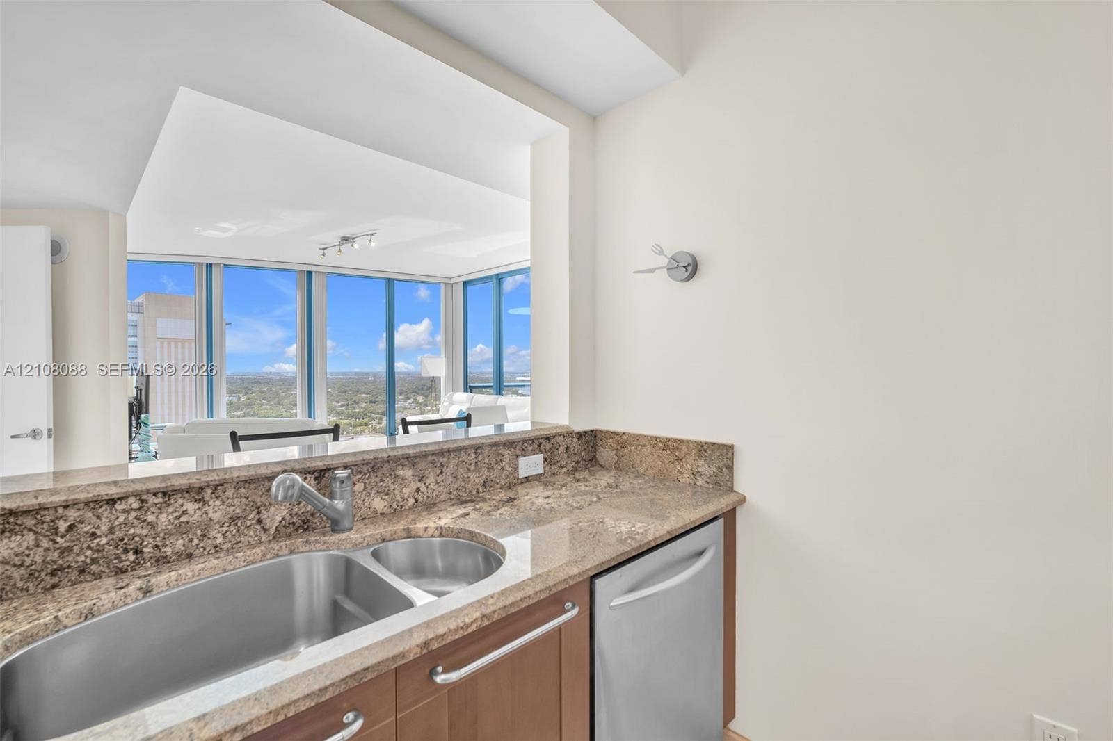 333 Las Olas Way, #2601, Fort Lauderdale, FL 33301 Kitchen featuring stone countertops, stainless steel dual-basin sink, high-arc faucet, built-in dishwasher, and wood cabinetry