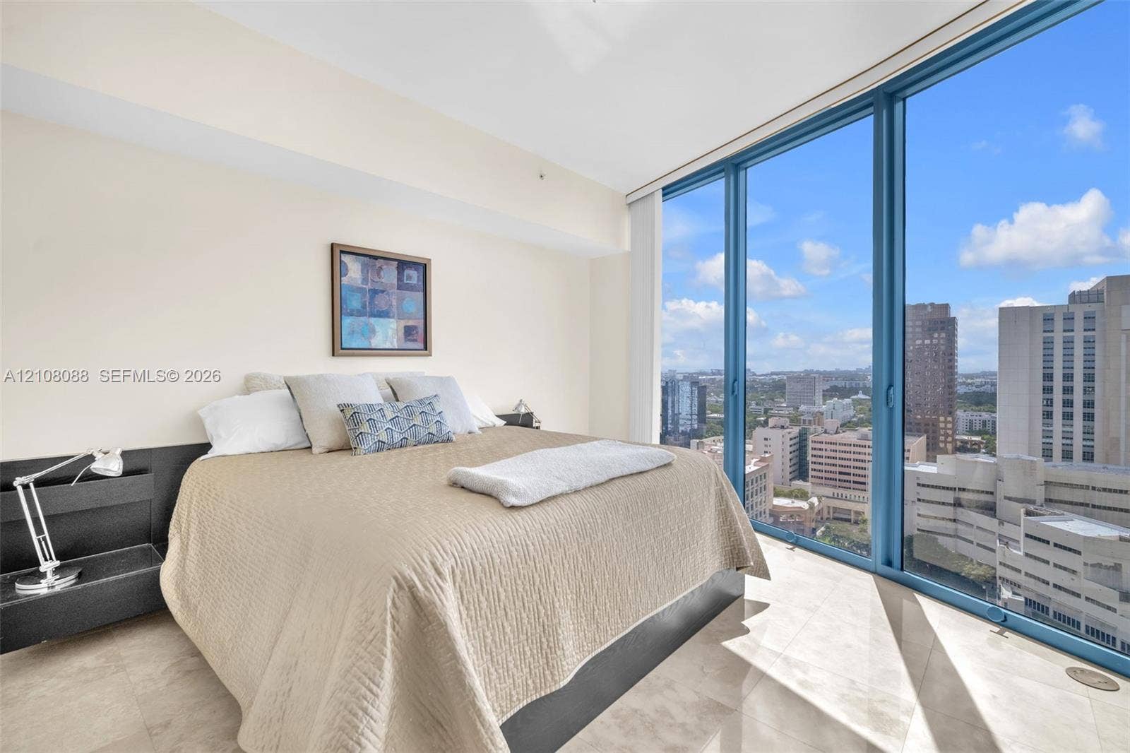 333 Las Olas Way, #2601, Fort Lauderdale, FL 33301 Floor-to-ceiling windows featuring urban scenery, expansive light-toned tile flooring, and a sleek, built-in dark finish headboard